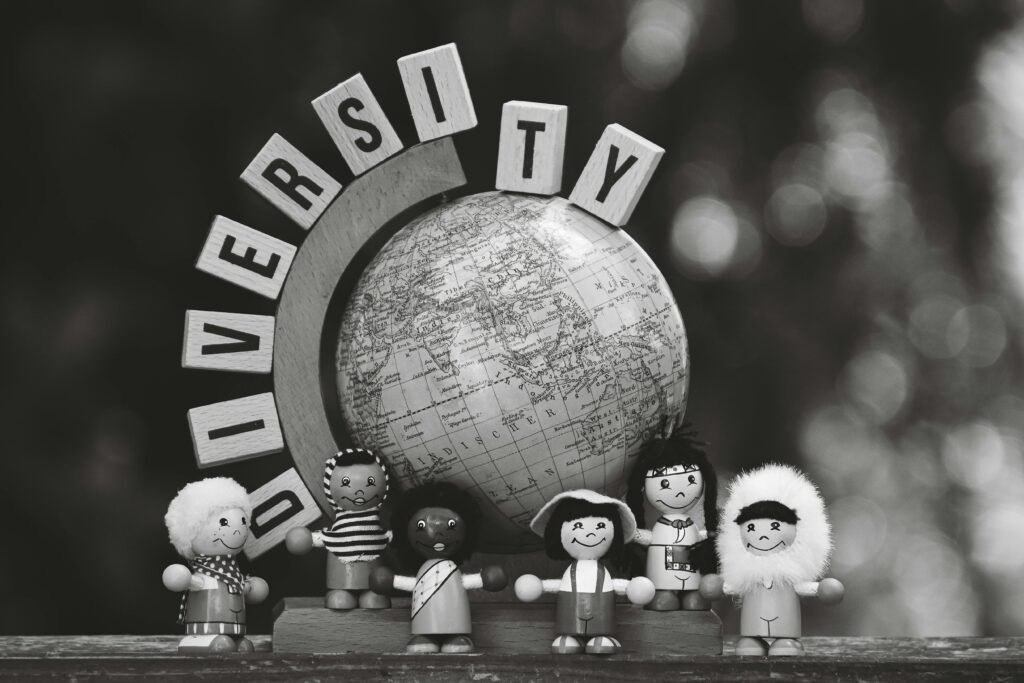 Black and white image of diverse wooden dolls and a globe representing cultural diversity.
